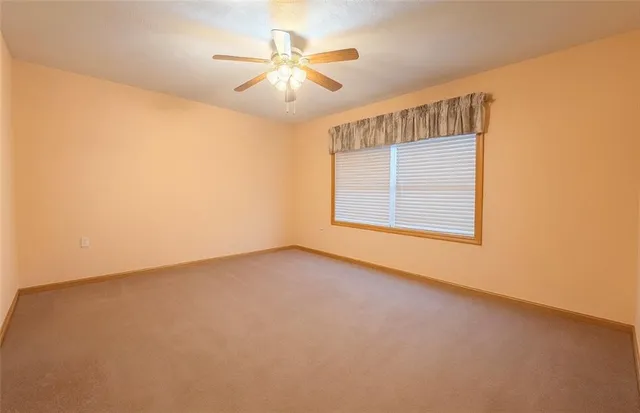 an empty room with windows and chandelier fan