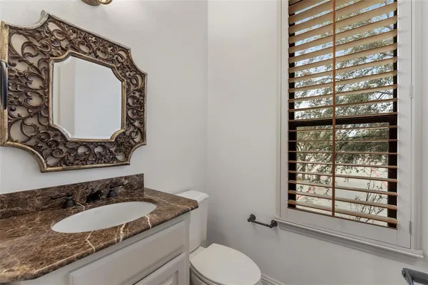 a bathroom with a granite countertop toilet sink and mirror