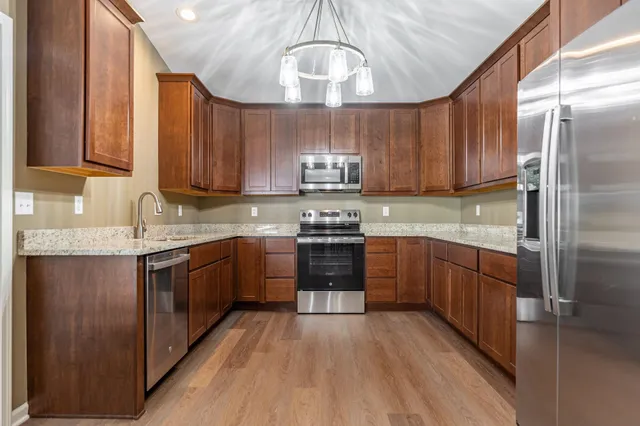 a kitchen with stainless steel appliances granite countertop a stove a sink dishwasher and a refrigerator