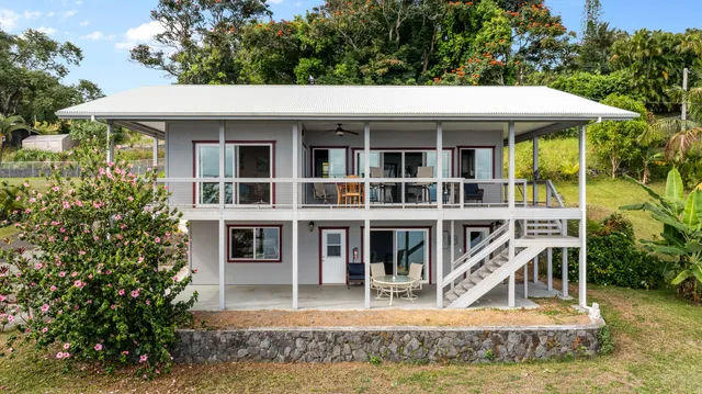 a view of a white house with large windows and a small yard