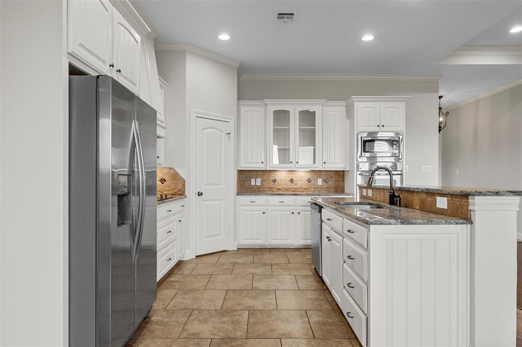 144 Ellis Farm Road Hewitt, TX 76643 - Photo 10 of 36 Kitchen featuring white cabinetry, stone tile flooring, a built-in stainless steel double oven and microwave, granite countertops, and a tile backsplash with integrated lighting