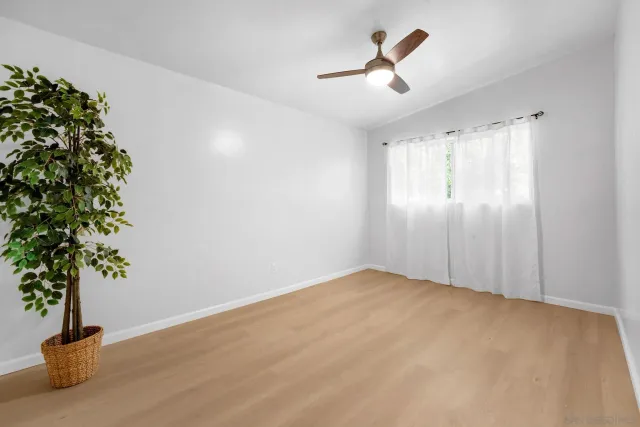 a view of empty room with plants and wooden floor