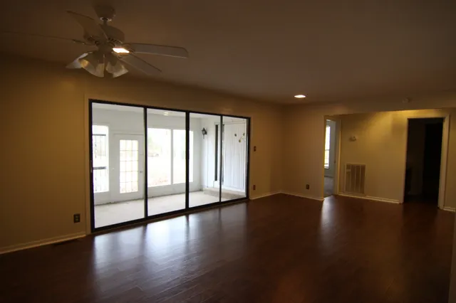 a view of an empty room with wooden floor and a window