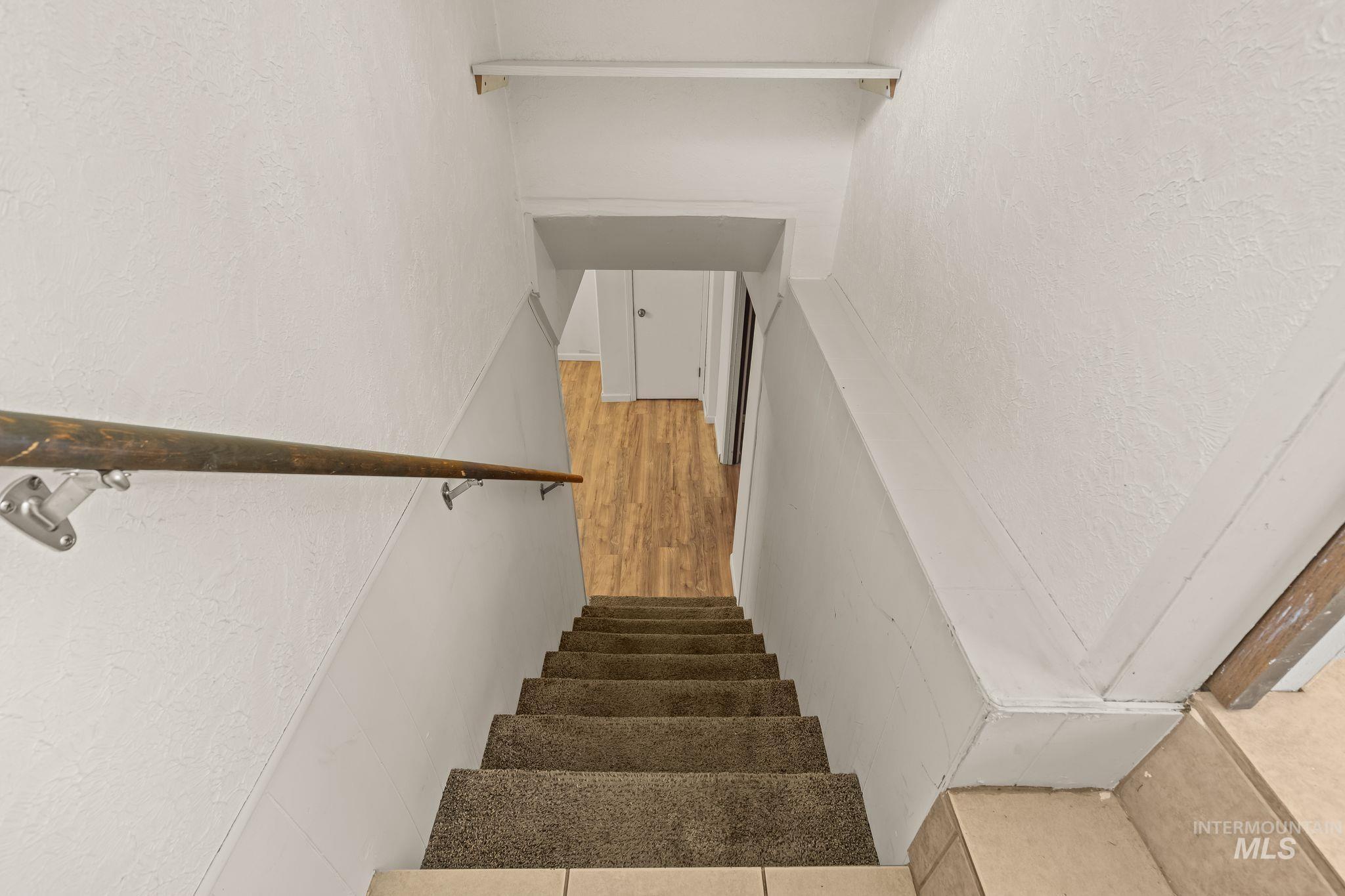 928 3rd Street Clarkston, WA 99403 - Photo 24 of 44 Carpeted staircase with a wood-finish handrail and white painted walls, leading to an area with wood-finish flooring