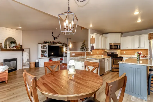 a kitchen with stainless steel appliances granite countertop a table chairs sink and cabinets