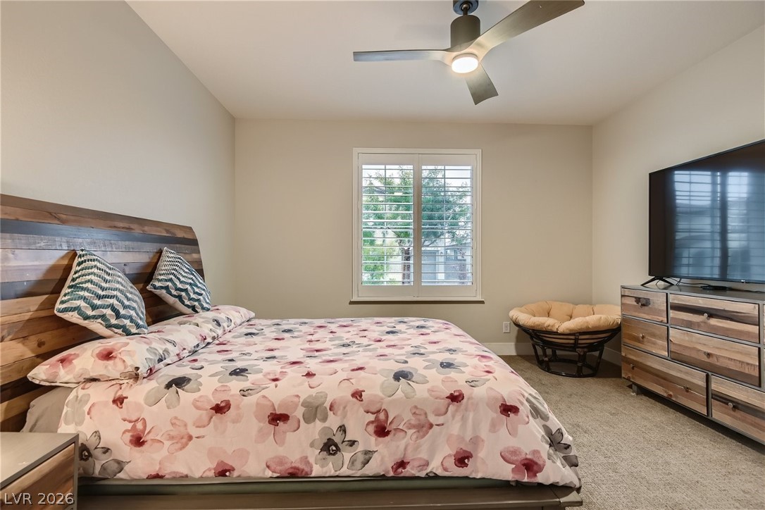 4631 Amazing View Street Las Vegas, NV 89129 - Photo 12 of 33 A well-lit bedroom with a wide window, plush carpeting, and a modern ceiling fan for comfort.