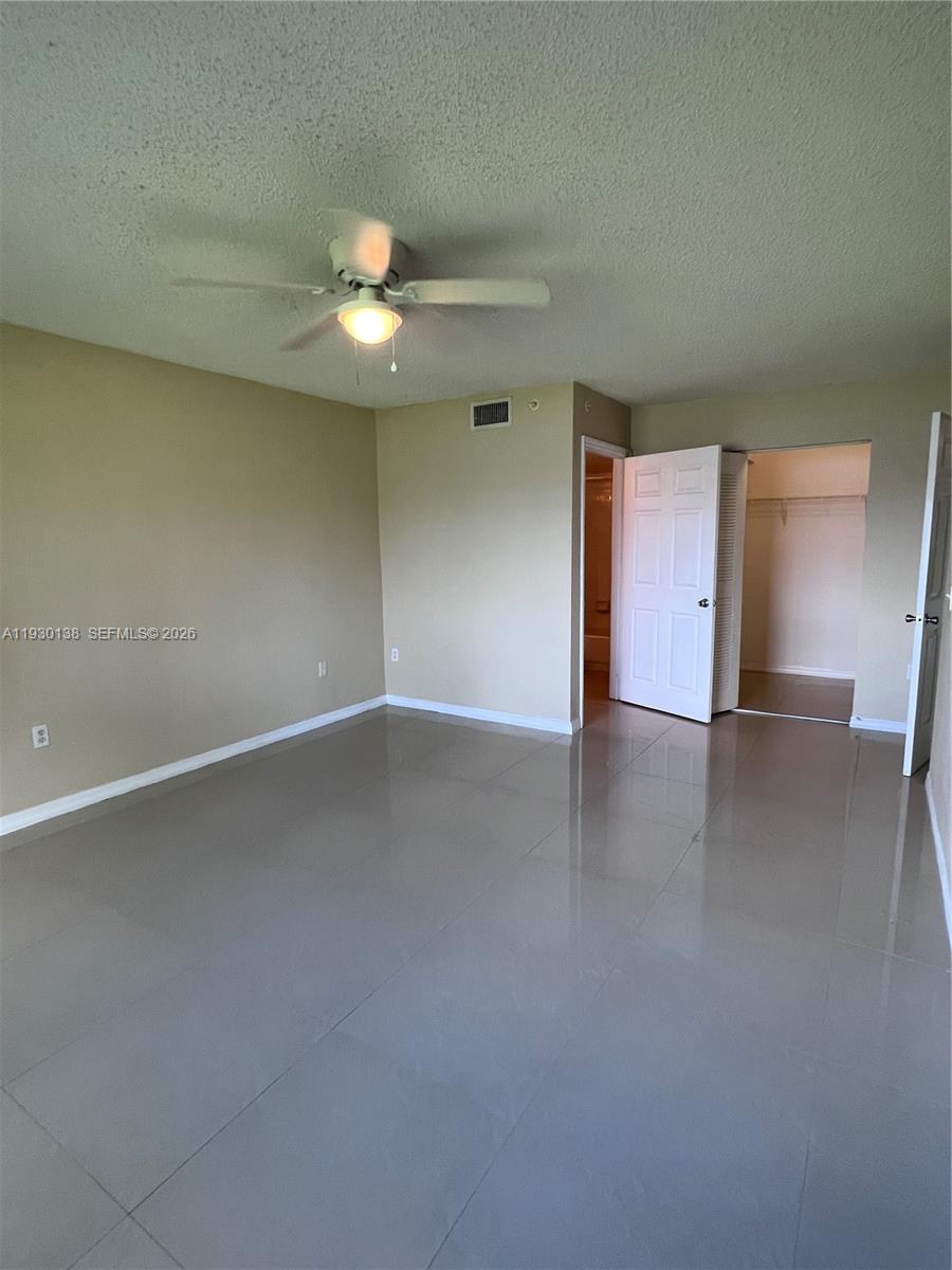 5061 Wiles Road, Unit 102 Coconut Creek, FL 33073 - Photo 7 of 14 an empty room with a empty space and a ceiling fan