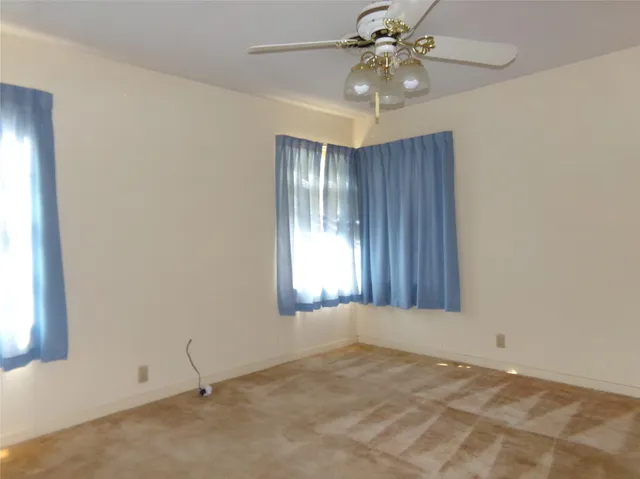 an empty room with windows and fan chandelier fan