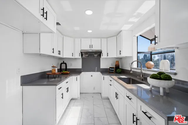 a kitchen with a sink white cabinets and white appliances