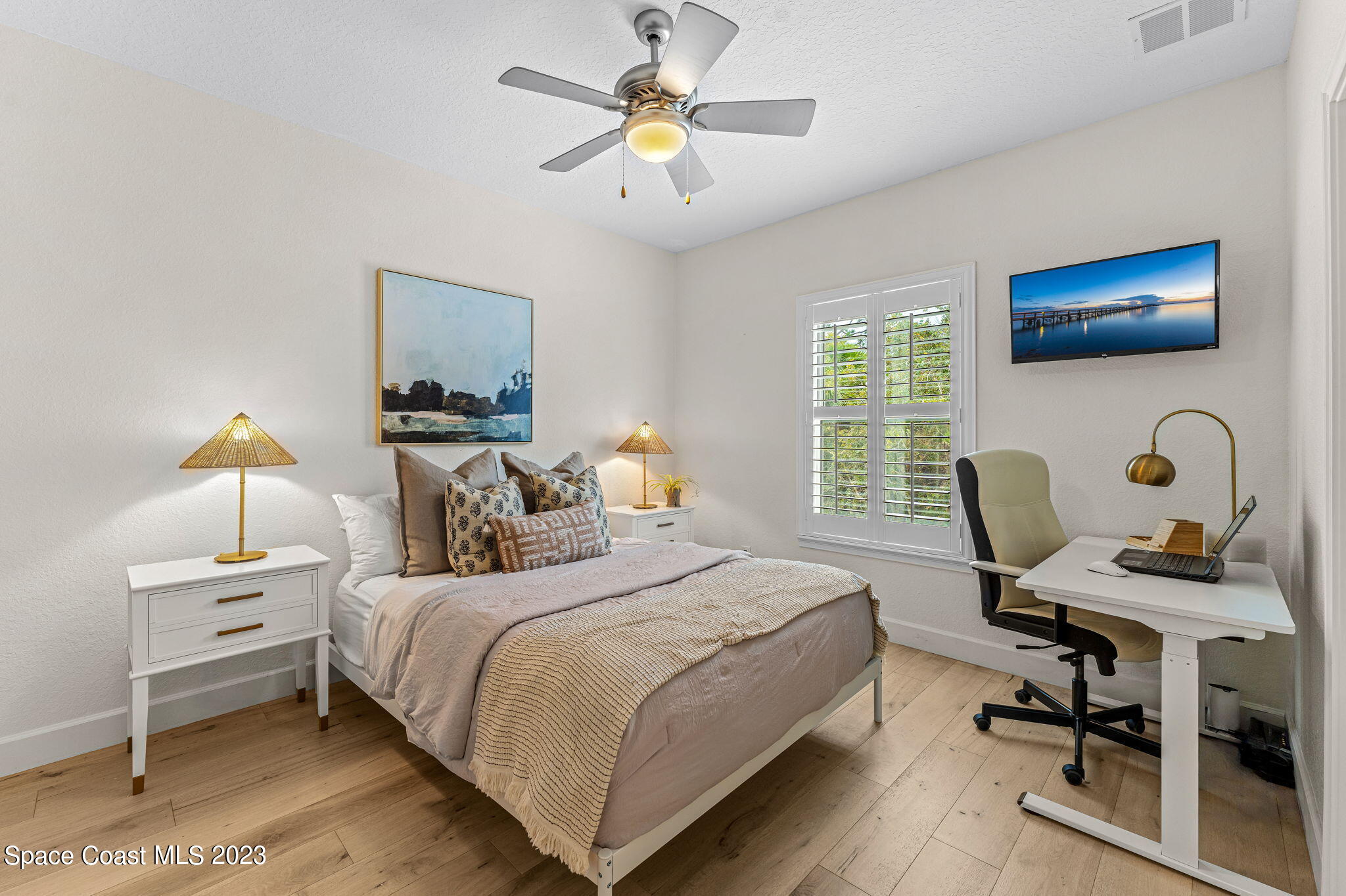 5595 Willoughby Drive Melbourne, FL 32934 - Photo 20 of 40 a bedroom with a bed a desk and chair with wooden floor