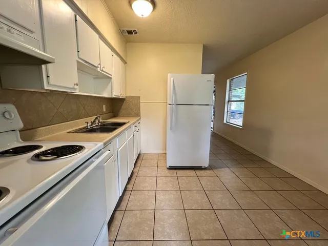 a kitchen with a sink a refrigerator and cabinets