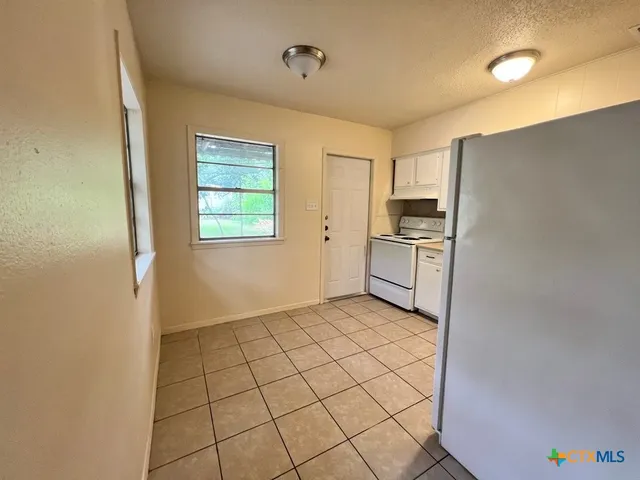 a view of a kitchen with a sink and dishwasher a refrigerator with white cabinets