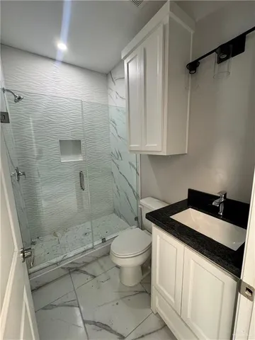 a bathroom with a granite countertop sink toilet and shower