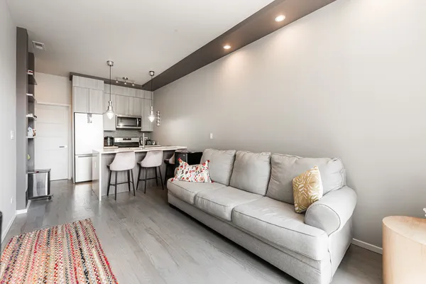a living room with stainless steel appliances furniture and a kitchen view