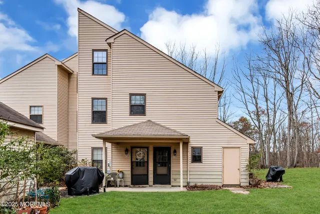 a view of a white house with large windows and a big yard with plants and large tree
