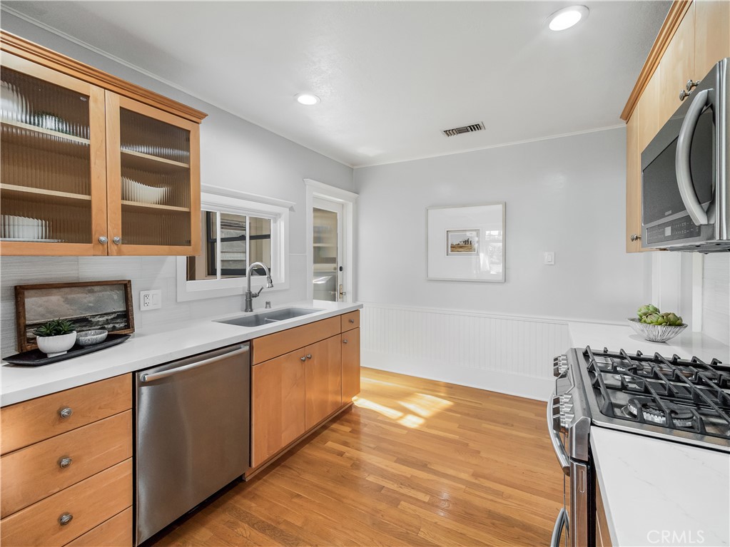 3740 East 5th Street Long Beach, CA 90814 - Photo 11 of 28 a kitchen with stainless steel appliances a stove a sink a refrigerator cabinets and wooden floor