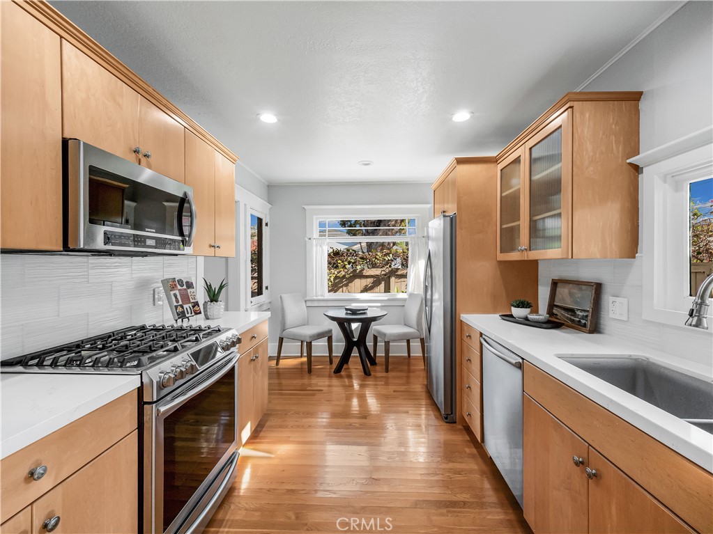 3740 East 5th Street Long Beach, CA 90814 - Photo 9 of 28 a kitchen with stainless steel appliances granite countertop a stove top oven a sink dishwasher a dining table and chairs with wooden floor