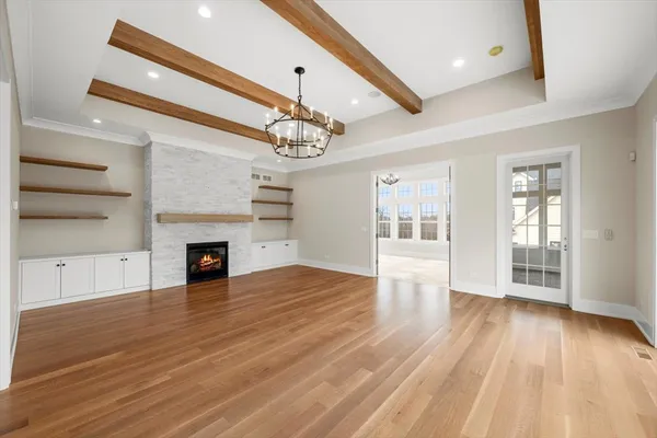 a view of an empty room with wooden floor fireplace and a window