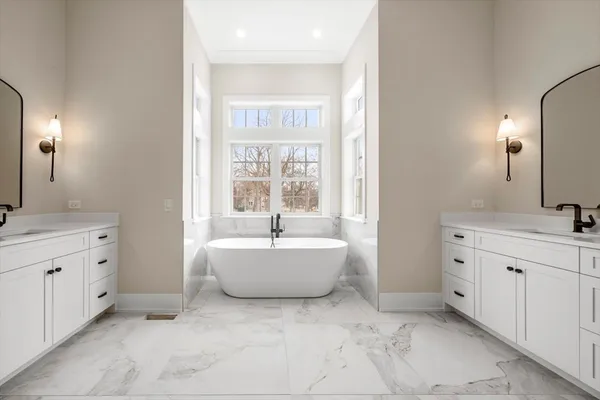 a spacious bathroom with double vanity a mirror a bathtub and vanity