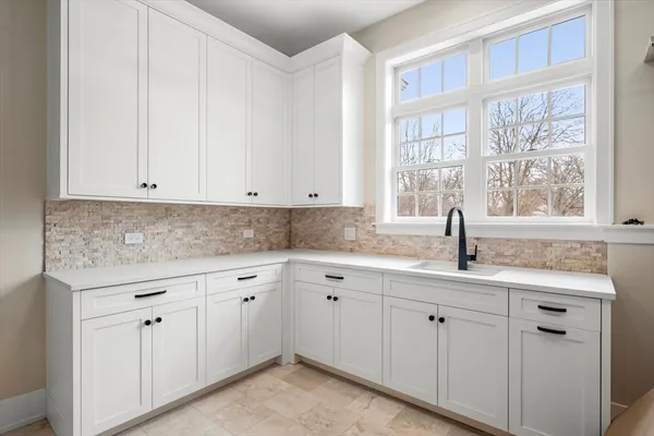 a kitchen with white cabinets and a window