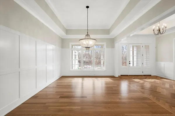 a view of an empty room with window and chandelier fan