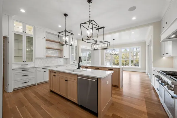 a kitchen with stainless steel appliances granite countertop a sink a stove and a wooden floors