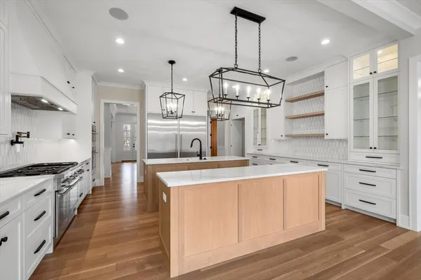 a kitchen with stainless steel appliances granite countertop a sink a stove and a wooden floors