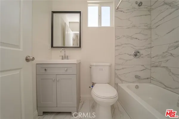 a bathroom with a toilet sink vanity tub and mirror