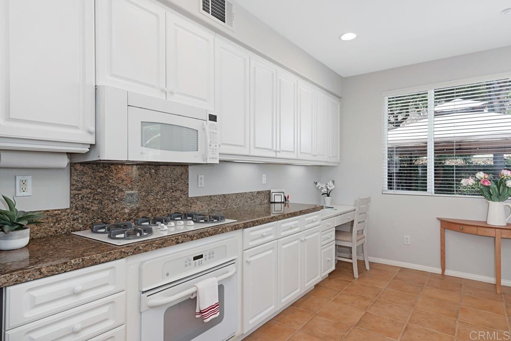 5595 Foxtail Loop Carlsbad, CA 92010 - Photo 13 of 28 a kitchen with granite countertop white cabinets and white appliances