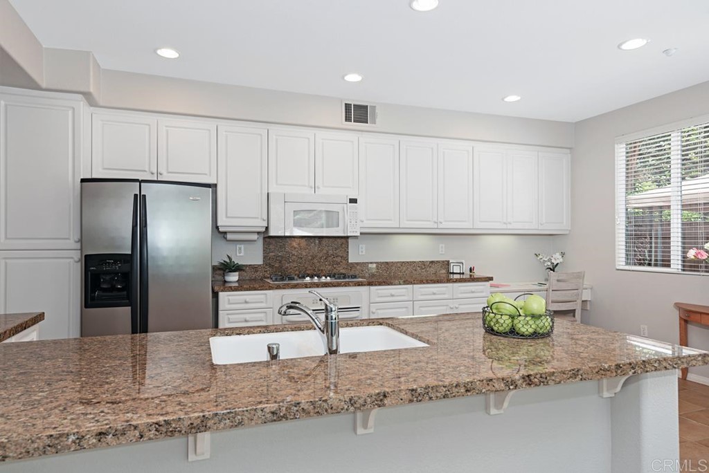 5595 Foxtail Loop Carlsbad, CA 92010 - Photo 9 of 28 a kitchen with stainless steel appliances granite countertop a sink refrigerator and stove