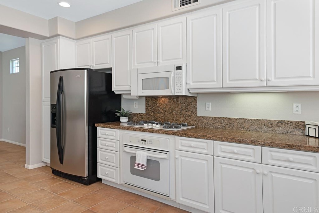 5595 Foxtail Loop Carlsbad, CA 92010 - Photo 10 of 28 a kitchen with granite countertop white cabinets and stainless steel appliances
