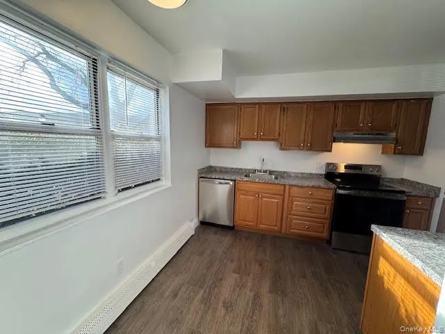 a kitchen with granite countertop a stove top oven a sink and dishwasher with wooden floor