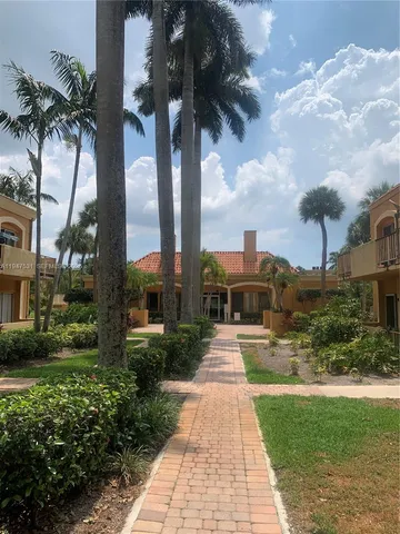 a view of a house with a yard and palm trees