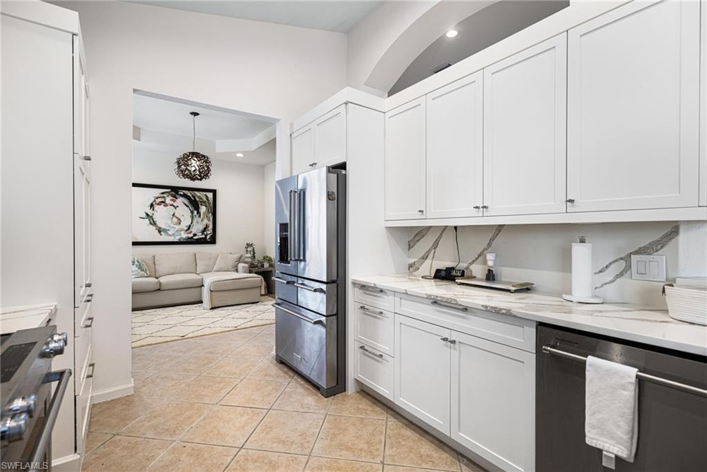 19071 Ridgepoint Drive, Unit 202 Estero, FL 33928 - Photo 8 of 26 Kitchen with light tile patterned flooring, white cabinetry, light stone countertops, and stainless steel appliances