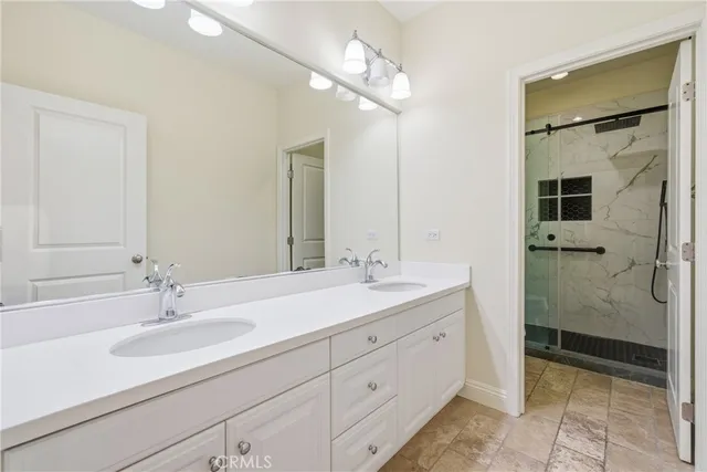 a bathroom with a double vanity sink mirror and shower