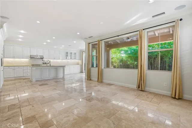 a view of a kitchen with large windows and cabinets