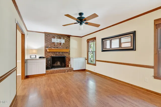 a view of a livingroom with a fireplace a ceiling fan and wooden floor