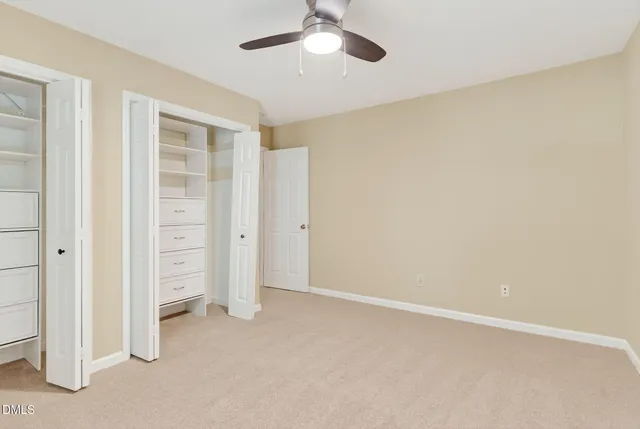 an empty room with a window and a chandelier fan
