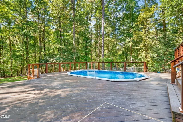 a view of backyard with swimming pool and trees in the background