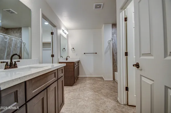 a spacious bathroom with a double vanity sink a mirror and a shower