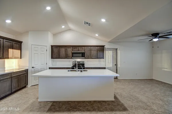 a large white kitchen with kitchen island a sink stainless steel appliances and window