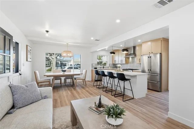 a living room with furniture kitchen view and a wooden floor