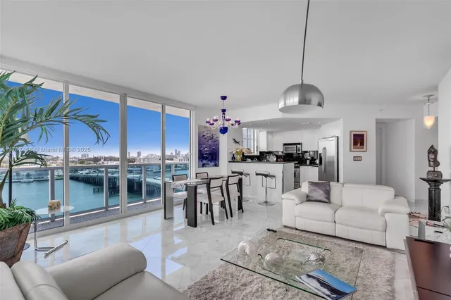 a living room with furniture a chandelier and kitchen view
