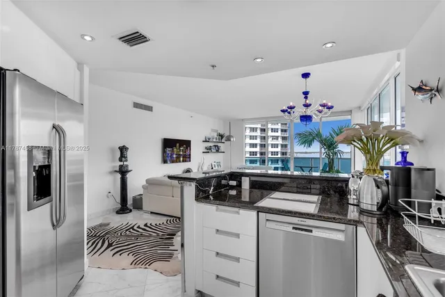 a kitchen that has a lot of white cabinets and stainless steel appliances