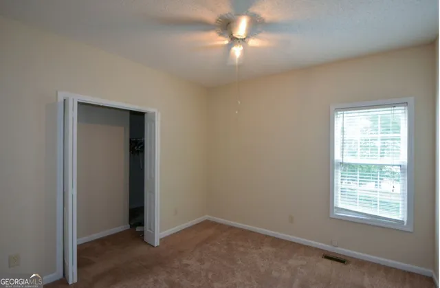 an empty room with windows and fan