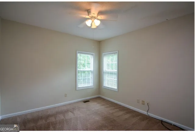 an empty room with windows and ceiling fan