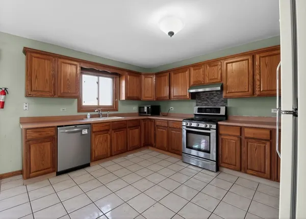 a kitchen with stainless steel appliances granite countertop a stove top oven a sink dishwasher and a refrigerator