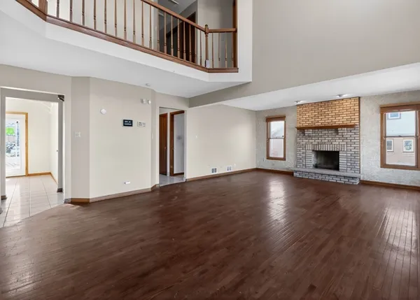 an empty room with wooden floor fireplace and windows