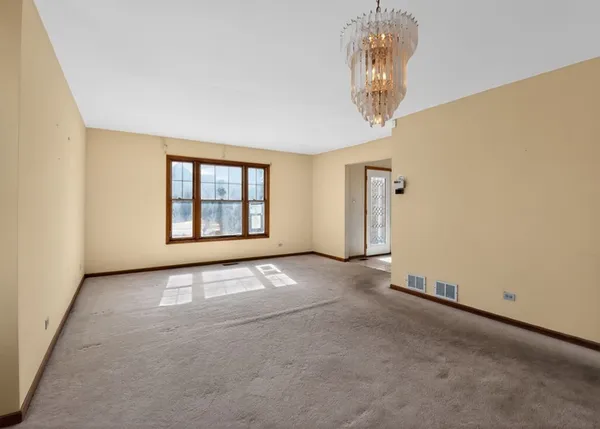 an empty room with a chandelier fan and windows
