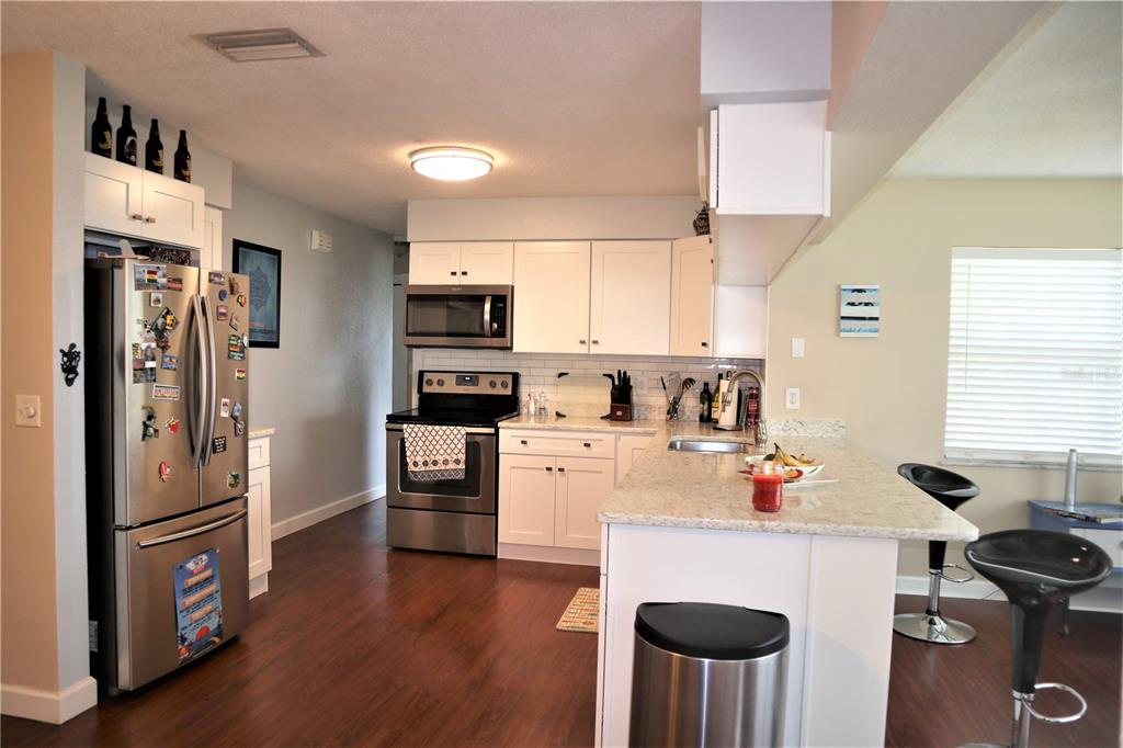 1468 South Evergreen Avenue Clearwater, FL 33756 - Photo 13 of 23 a kitchen with a refrigerator a stove a microwave and white cabinets